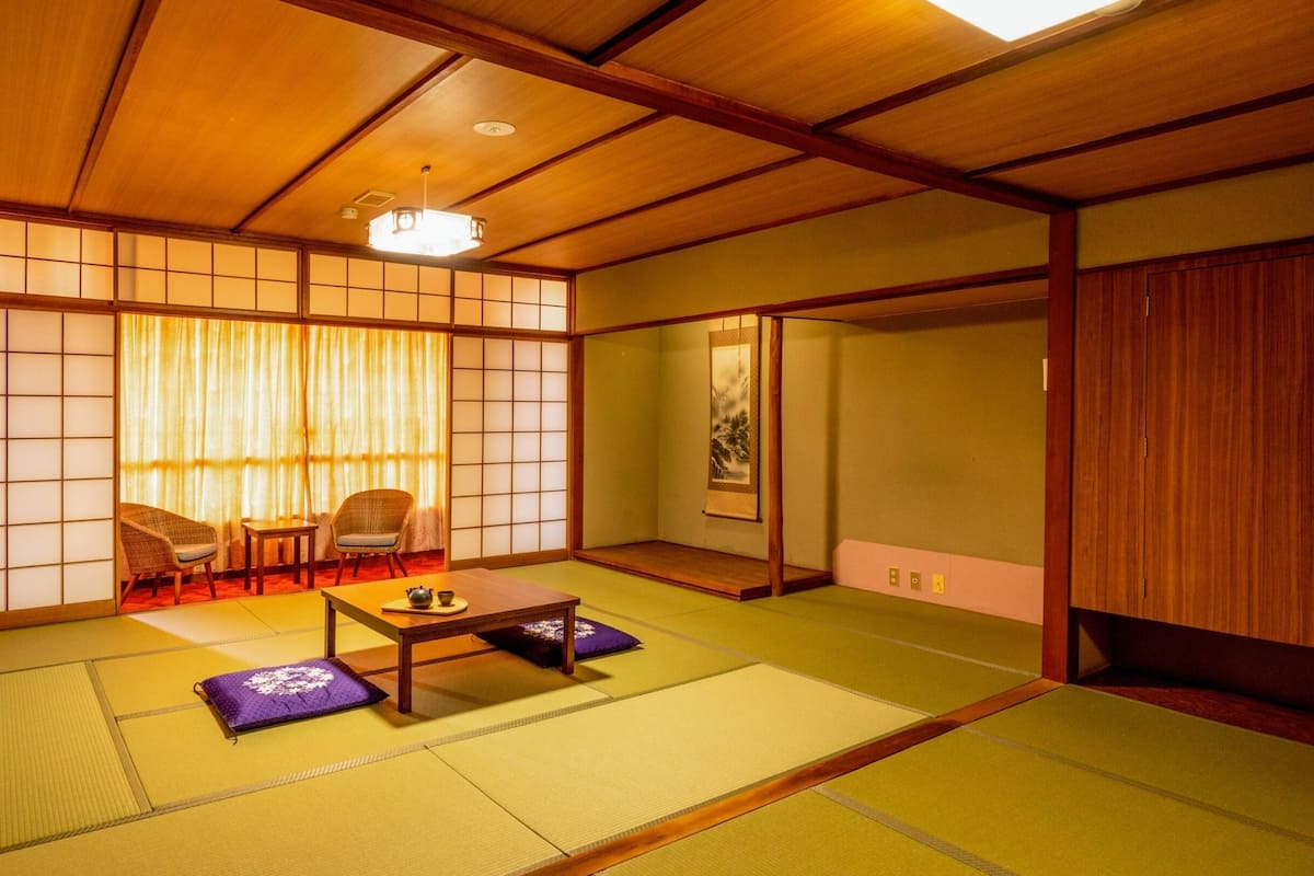 Ein traditioneller japanischer Raum mit Tatami-Böden, einem niedrigen Tisch mit Teeservice und Schiebetüren.