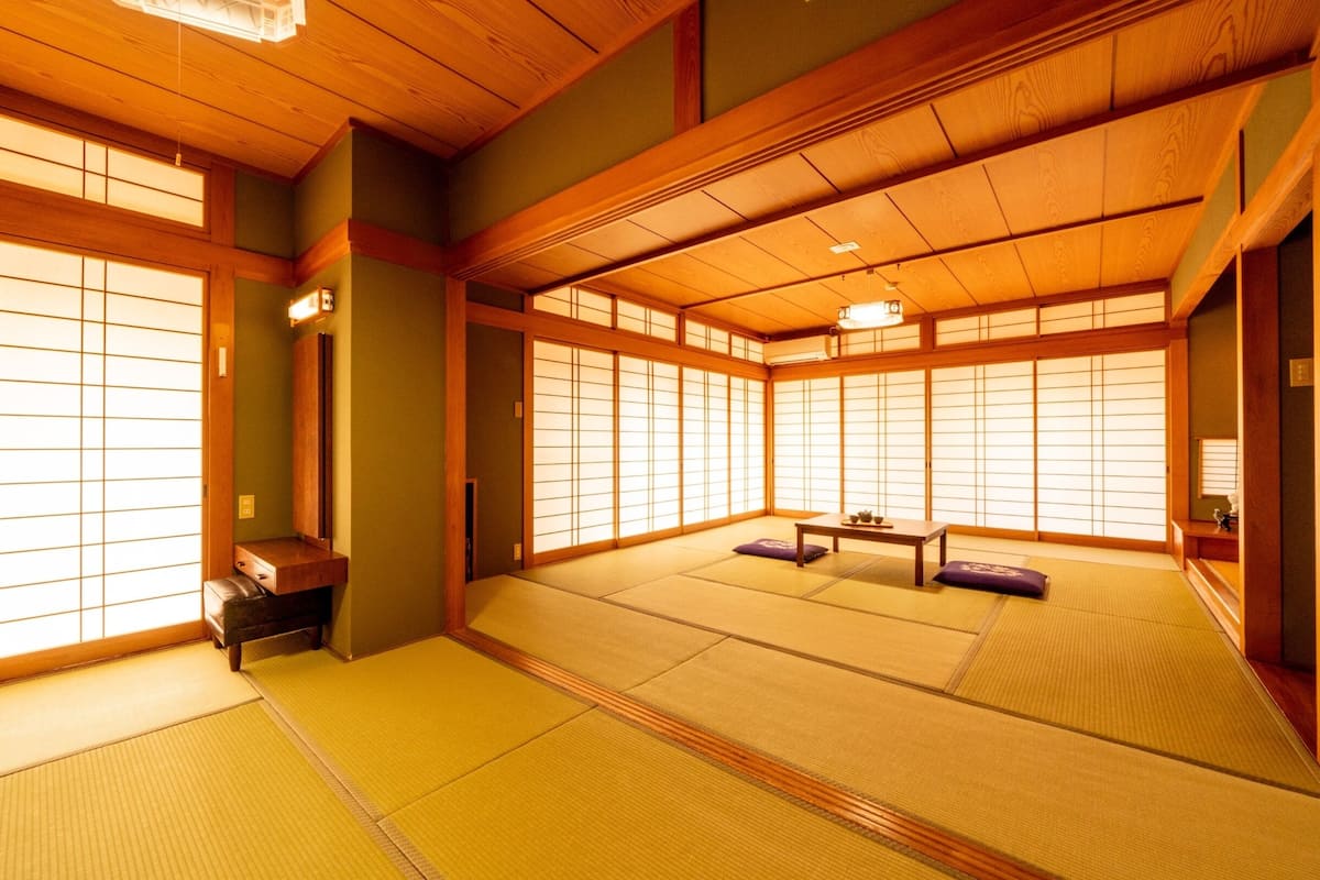 Ein traditioneller japanischer Raum mit Tatami-Böden, verschiebbaren Shoji-Türen und einer niedrigen Holzbalkendecke.