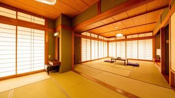 Ein traditioneller japanischer Raum mit Tatami-Böden, verschiebbaren Shoji-Türen und einer niedrigen Holzbalkendecke.