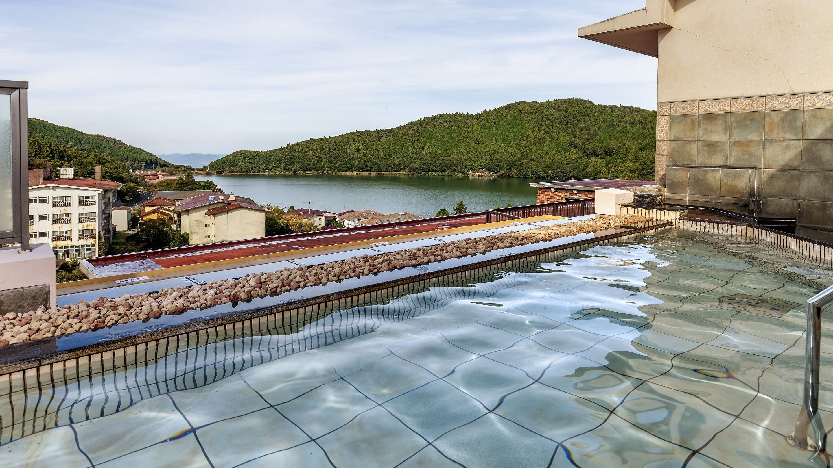 Piscina en la azotea con vistas a un lago y colinas.