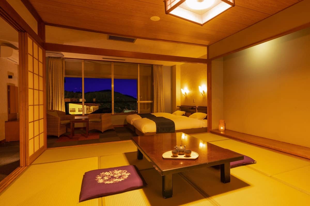 Ein traditioneller japanischer Raum mit Tatami-Böden, einem niedrigen Holztisch und einer Couch mit Kissen.
