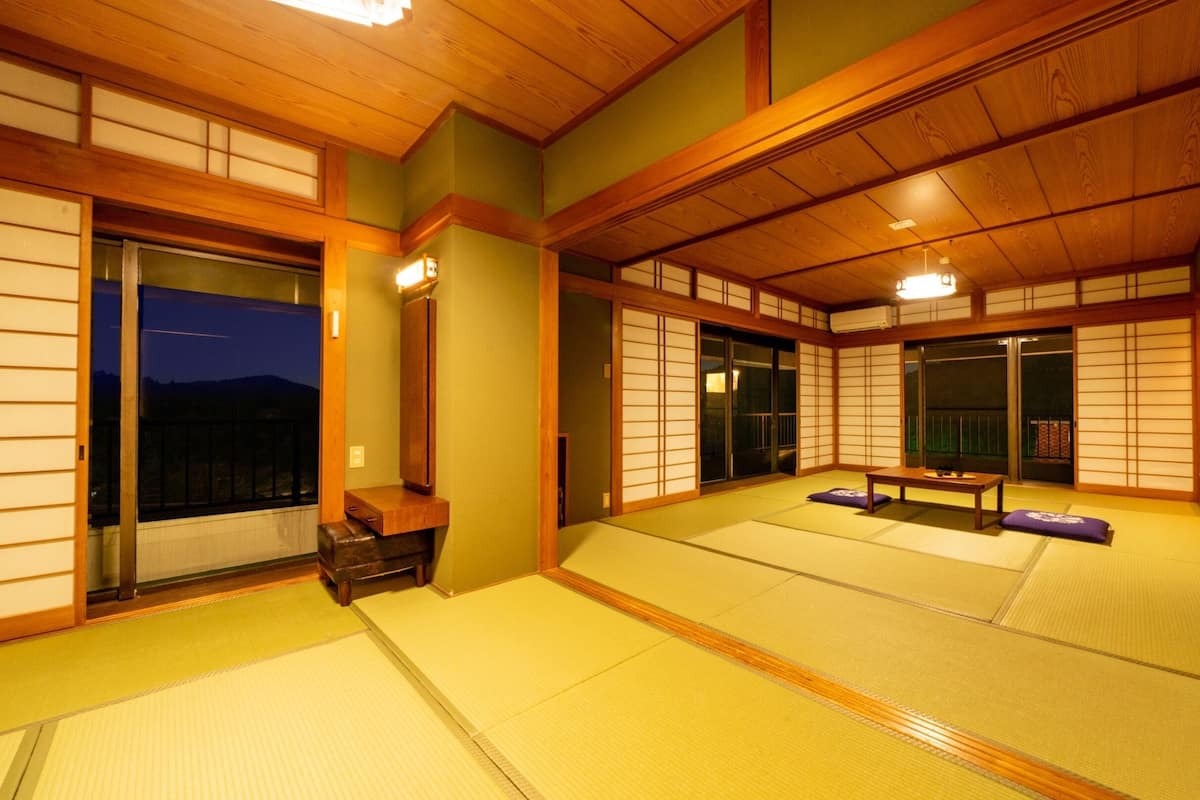 Ein traditioneller japanischer Raum mit Tatami-Böden, Schiebetüren und einem niedrigen Holztisch.
