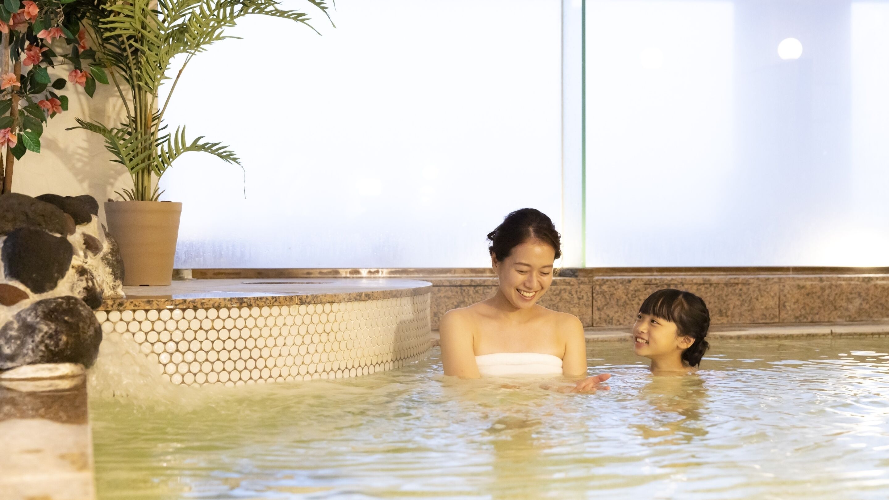 A spa area with a stone wall, a potted plant, and a tiled floor.
