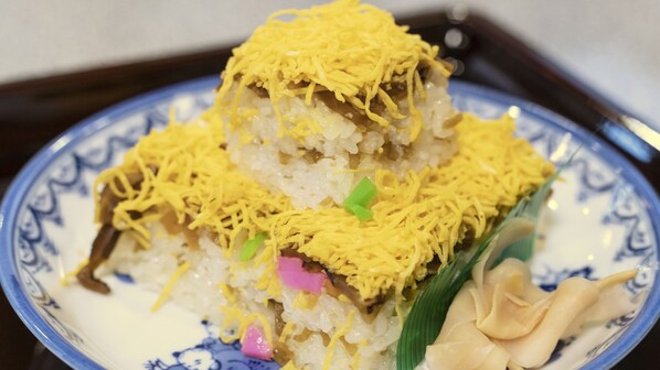 A plate of food with rice, vegetables, and shredded yellow topping.