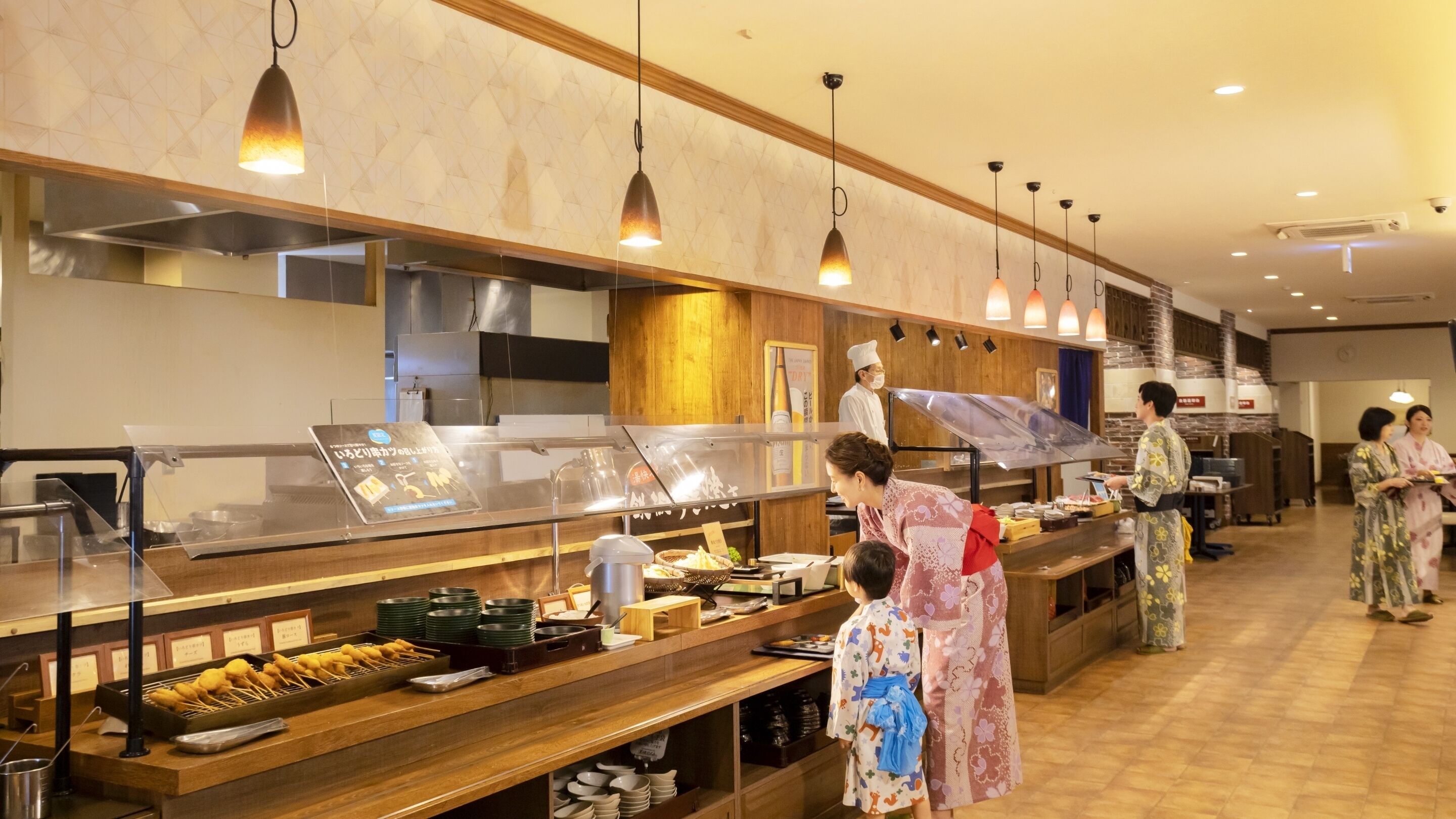 A buffet setup with various food items and a staff member serving.