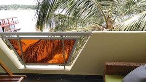 Un balcón con vistas al mar, una silla de madera y un sofá de mimbre.