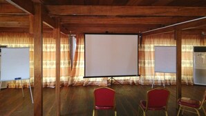 Una sala de conferencias con techo de madera, dos pizarras blancas y tres sillas rojas.