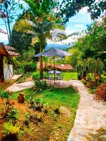 A garden with a stone pathway, a table with chairs, and a large umbrella.