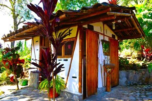 A small, rustic hut with a thatched roof, surrounded by lush tropical plants. - Hotel la Casa de Francois - Hostel (San Agustin)