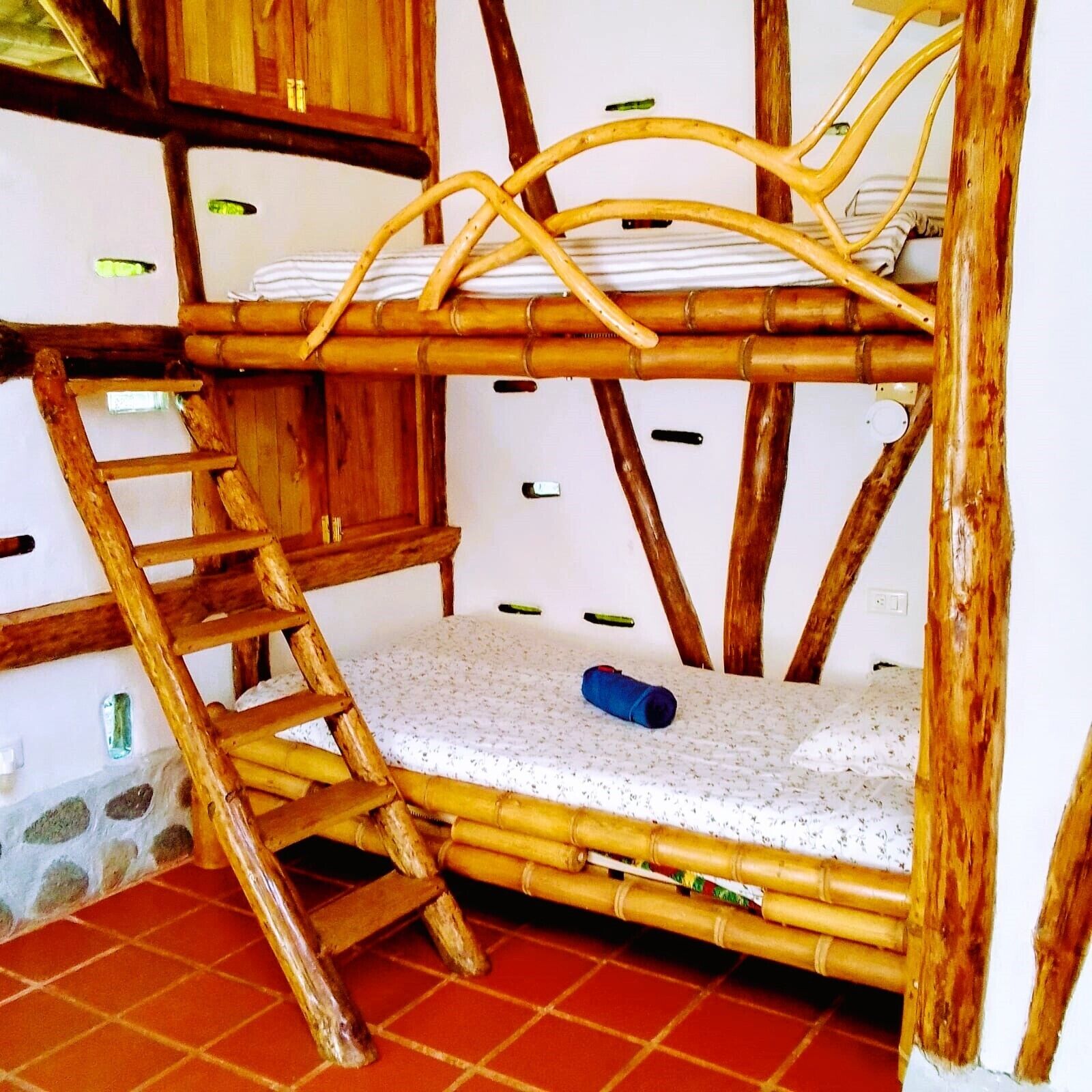 A bunk bed with a ladder, a small mattress on the lower bunk, and a blue object on the mattress.