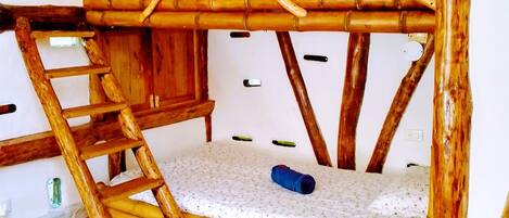 A bunk bed with a ladder, a small mattress on the lower bunk, and a blue object on the mattress.
