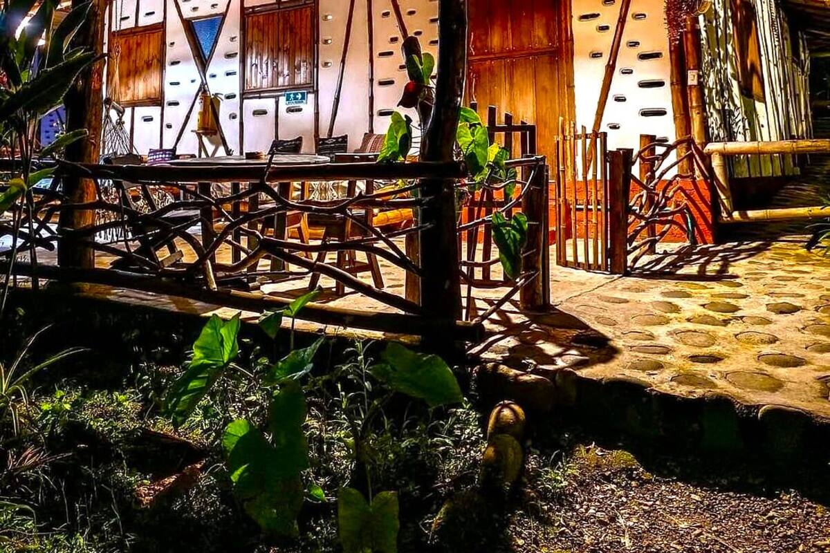 Una cabaña de madera rústica con techo de metal, rodeada de vegetación.