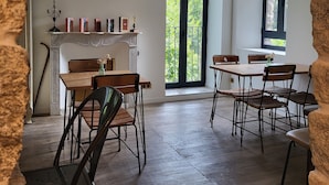 A dining area with a fireplace, wooden flooring, and a view of greenery outside. - A Bella Scusa (Bastelica)