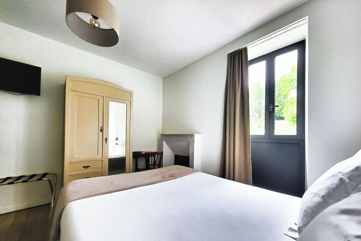 Habitación de hotel con cama, armario, escritorio y ventana con cortinas.