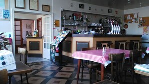 Un restaurante con barra, manteles a cuadros y piso de baldosas.