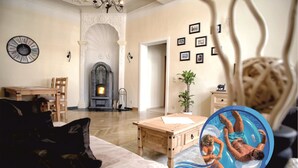 A living room with a fireplace, a dining area, and a pool area. - City Apartments Mühlhausen (Mühlhausen/Thüringen)