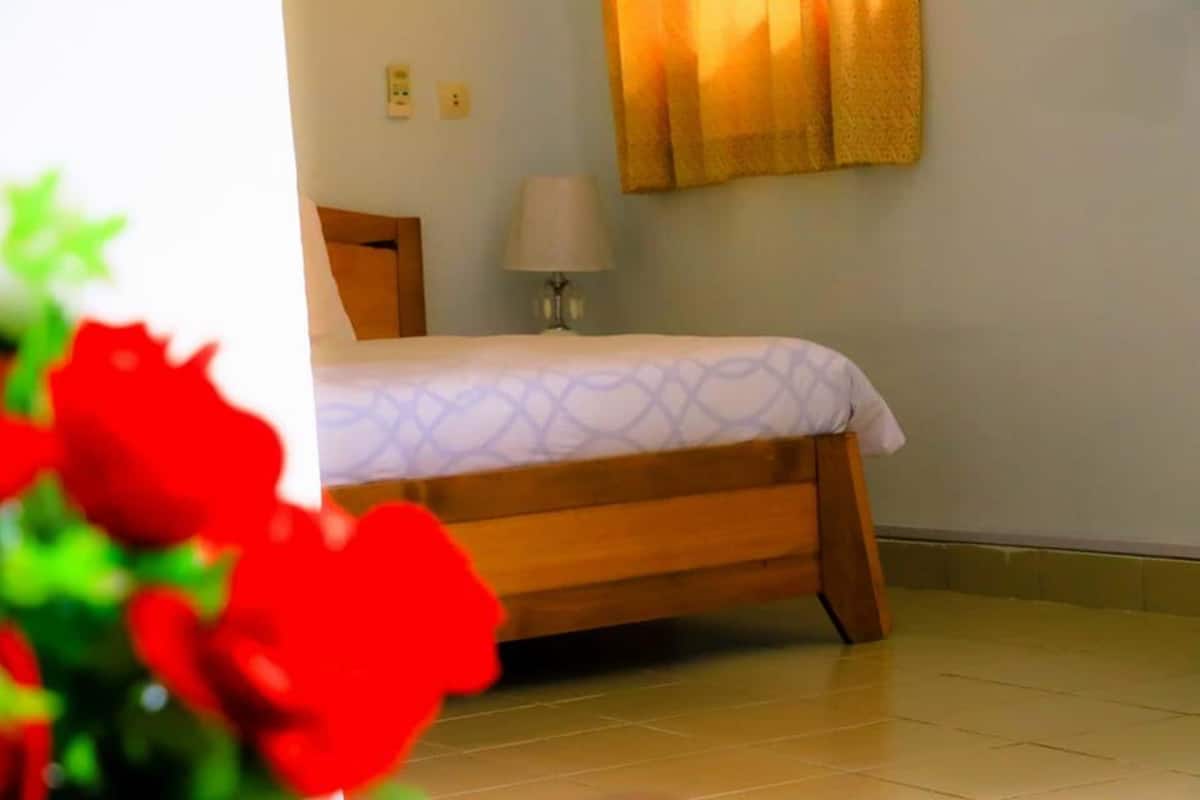 Une chambre à coucher avec un lit, une lampe de chevet et une fenêtre avec des rideaux.