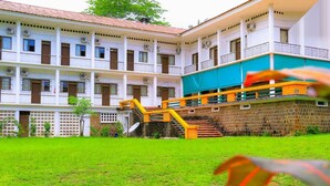 A multi-story building with balconies, a staircase with yellow railings, and a grassy courtyard. - Complexe Hôtelier Food And Business (Abidjan)