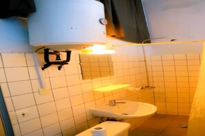 A small bathroom with a toilet, sink, and a mirror.