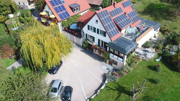 Propiedad residencial con varios paneles solares, un patio cubierto y una zona de estacionamiento.
