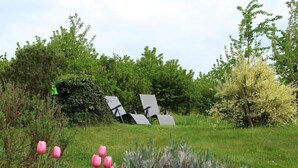 Un jardín con césped, tulipanes rosados y una escultura de metal.