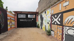 Una entrada amb una reixa negra amb la inscripció “seedspace” i un mural colorit a la paret propera.