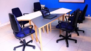 Una sala de conferències amb una taula, quatre cadires, un ordinador portàtil i una pissarra.