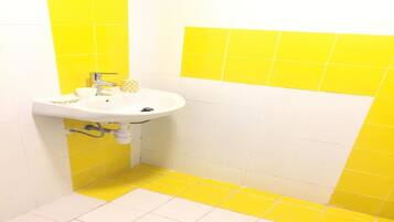 A bathroom with a white sink, yellow and white tiled walls, and a yellow floor.