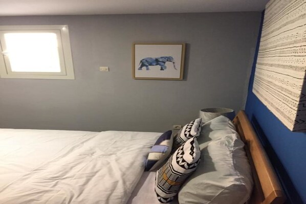 A bedroom with a bed, pillows, a framed picture, and a window. - Hotel Seedspace Abidjan (Abidjan)