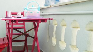 A red chair and table with a teapot and cups on a balcony with white walls and a blue sky in the background. - A Casa Di CI (Acquaviva delle Fonti)