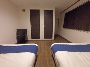 A room with two beds, a wardrobe, a small table, and a window with curtains. - TERRACE HOUSE Bentencho (Osaka)