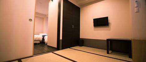 A hotel room with tatami mats, a bed, a wardrobe, a television, and a small table.