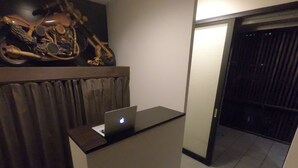 A modern reception desk with a laptop, a dark curtain, and a wooden panel.