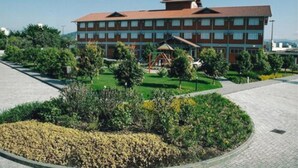 Hotel de varios pisos con un patio central, rodeado de follaje y un sendero pavimentado.