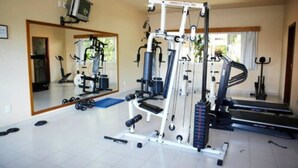 Un gimnasio en casa con una cinta de correr, banco de pesas y varias máquinas de ejercicio.