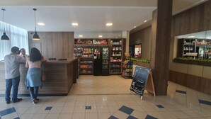 Un área de recepción con un mostrador de madera, un cartel que dice 'Recepção' y un refrigerador lleno de bebidas.
