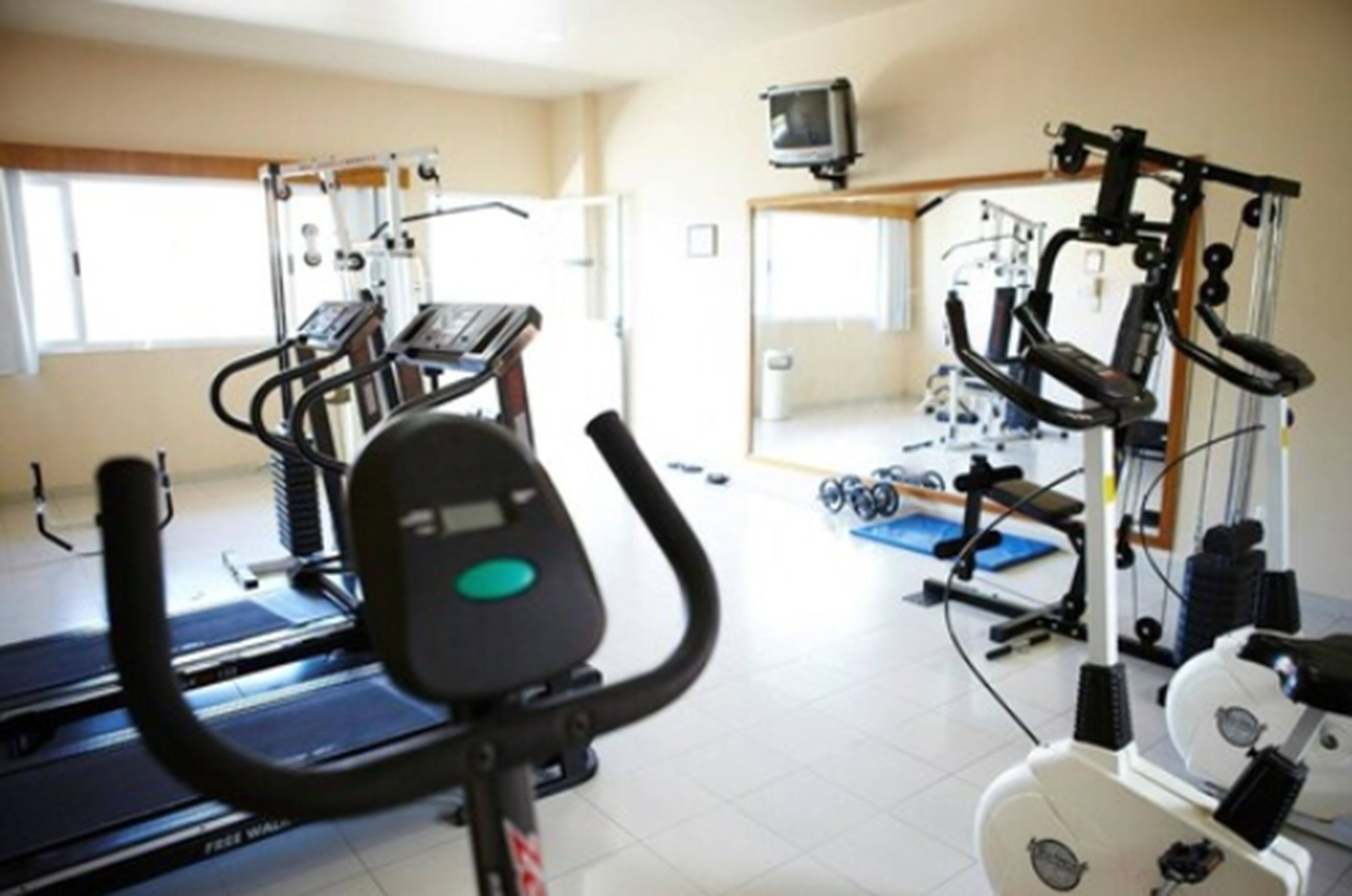 Ginásio com esteiras, elípticos e equipamentos de musculação.