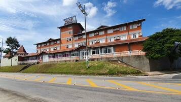 Un hotel de varios pisos con un letrero llamativo que dice 'Brésil Palace Hotel' y un restaurante.