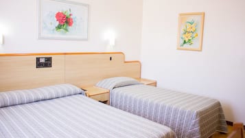 A hotel room with two single beds, a headboard with a control panel, and two wall-mounted light fixtures.