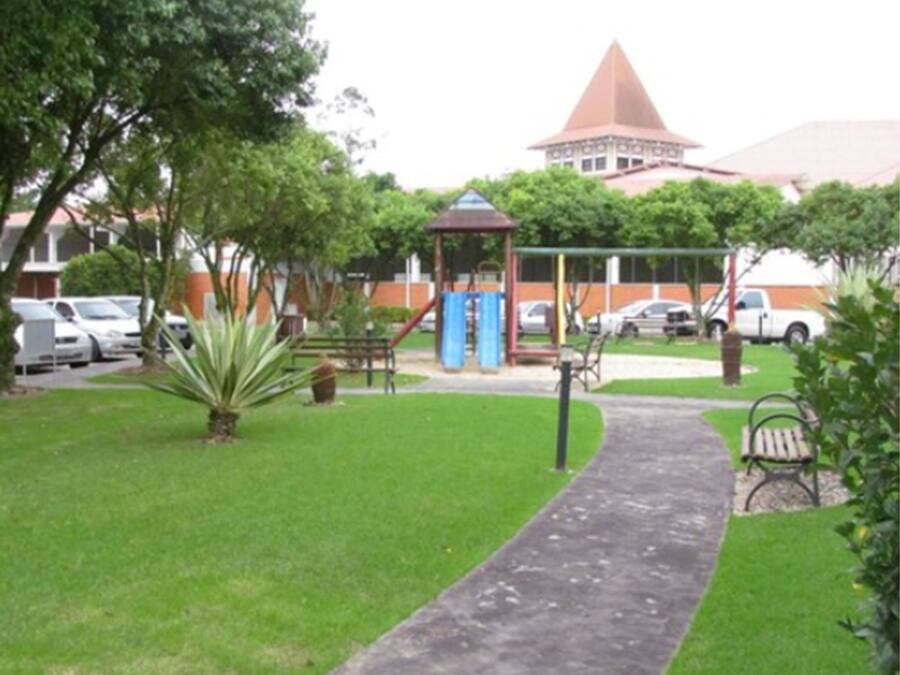 Un parque con un área de juegos, un pabellón y un sendero pavimentado.