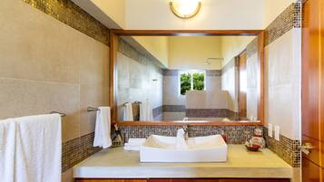 A bathroom with a large mirror, a sink, and wooden cabinets.