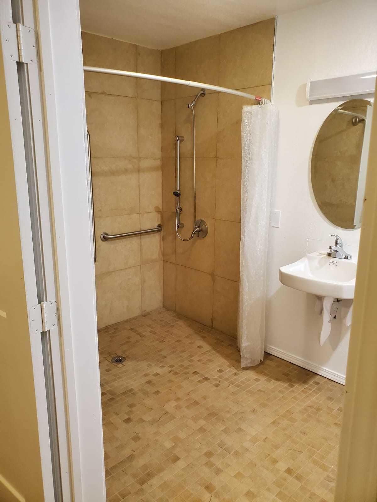 Un bany amb dutxa, un lavabo blanc i un mirall.