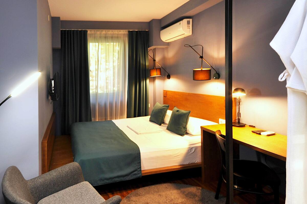 Ein Hotelzimmer mit Bett, Schreibtisch, Stuhl und Klimaanlage.