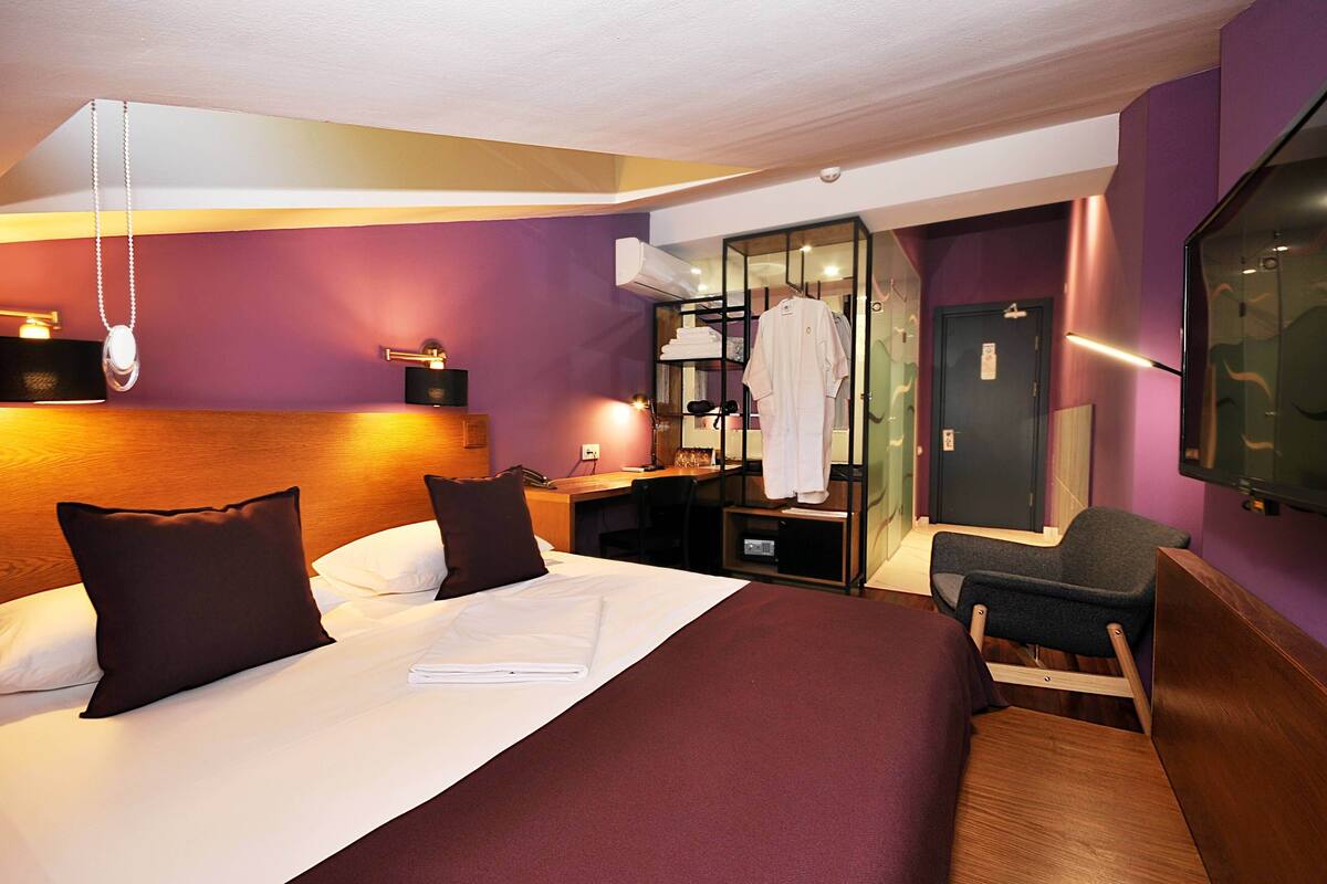 Ein Hotelzimmer mit Bett, Schreibtisch, Stuhl und Fernseher.