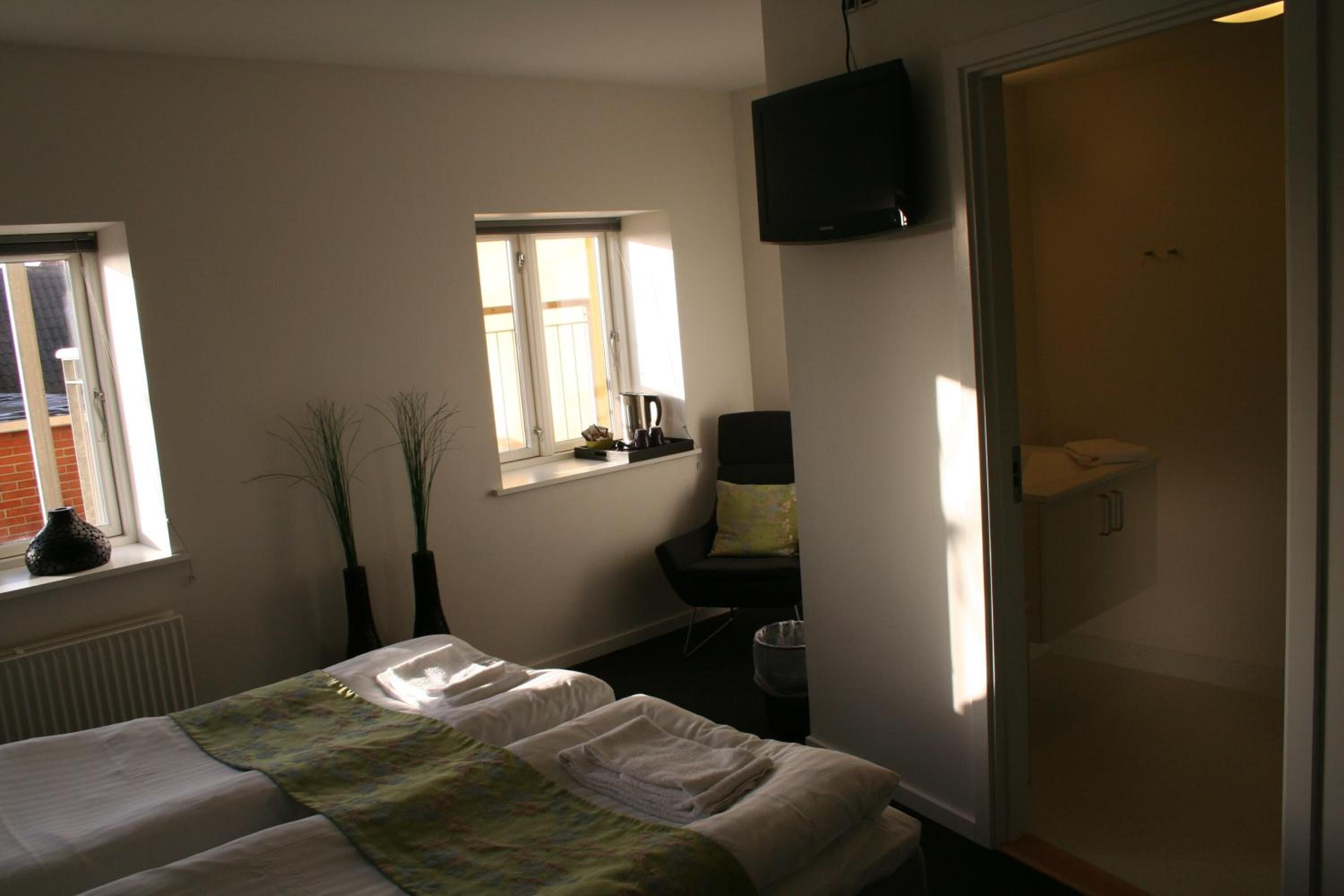 Ett hotellrum med två sängar, en tv, ett fönster och ett badrum.