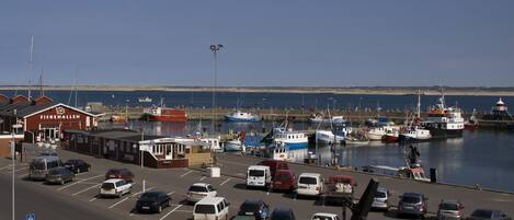 A marina with boats docked, a parking lot with cars, and a building labeled 'FISKEHALLEN'.