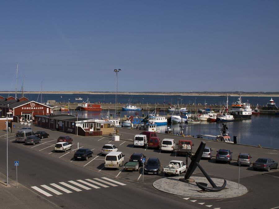 A marina with boats docked, a parking lot with cars, and a building labeled 'FISKEHALLEN'.