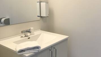 Un baño moderno con lavamanos, espejo y mueble blancos.