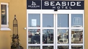 Het uiterlijk van Hotel Seaside, met een goed zicht op de ingang en een grote potplant aan de linkerkant.