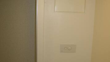 A small, clean bathroom with a toilet, a hand dryer, and a toilet paper holder.
